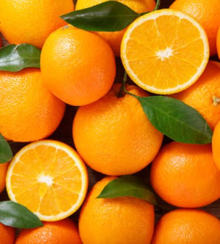 fresh orange fruits with leaves as background, top view